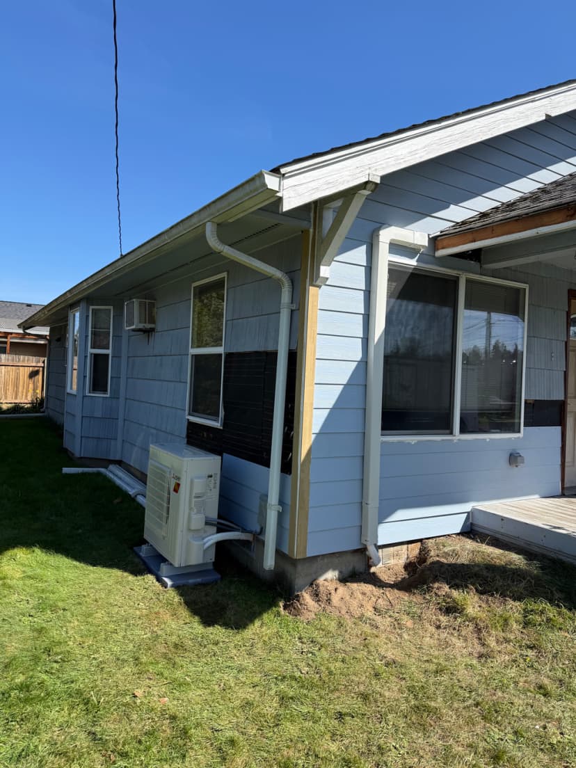 Side view of a house with an air conditioning unit and clear blue sky.